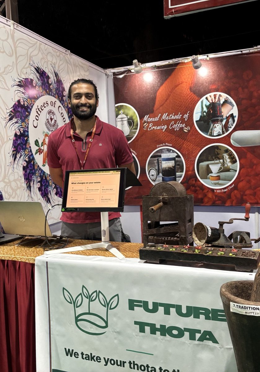 Appanna standing at the Future Thota stall in the Coffee Board pavilion, beside a screen showing the ThotaTracker assistant